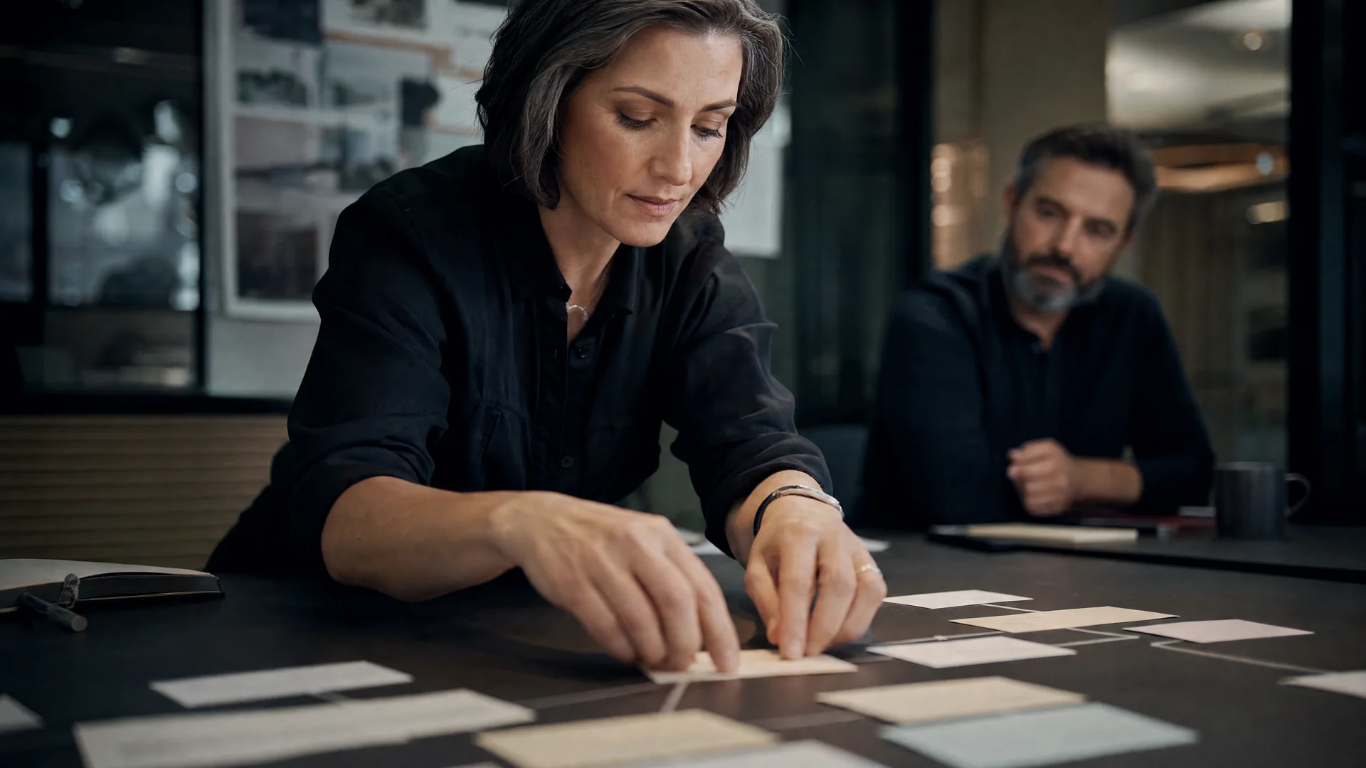 Two colleagues assemble a shared workflow from cards arranged across a table.