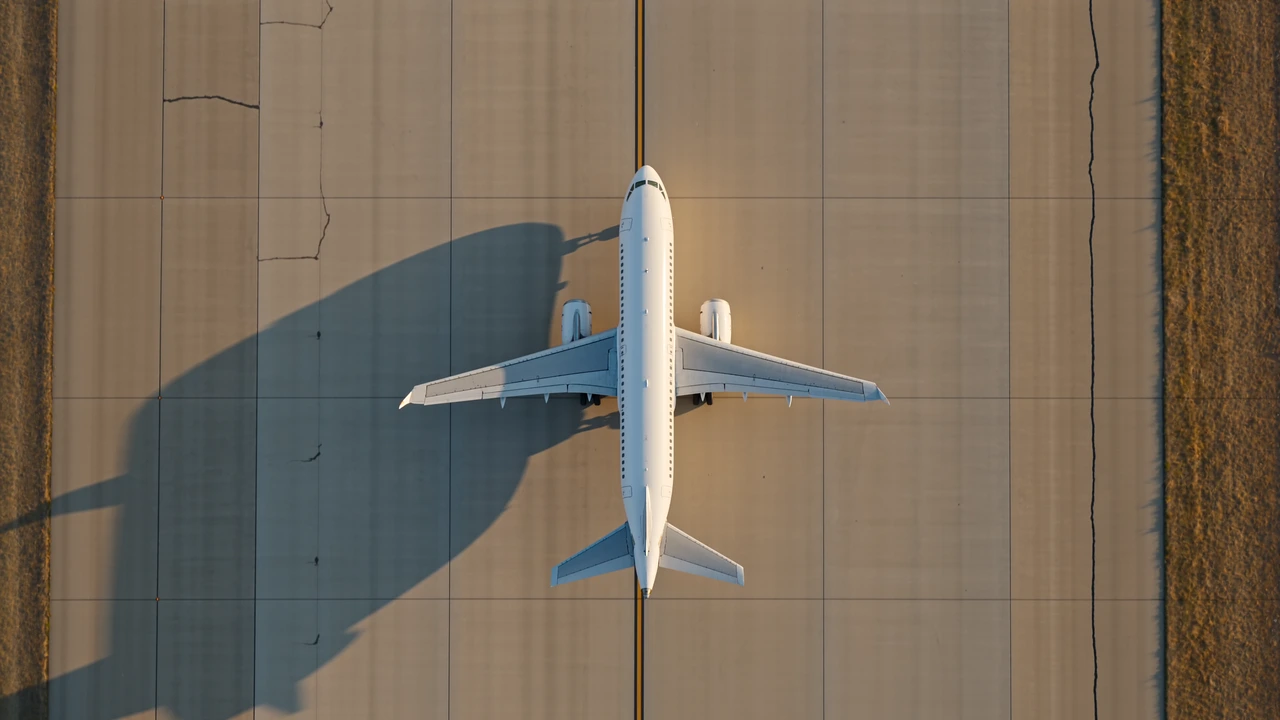 Vista aérea ilustrativa de una aeronave avanzando por una calle de rodaje bajo la cálida luz del sol.