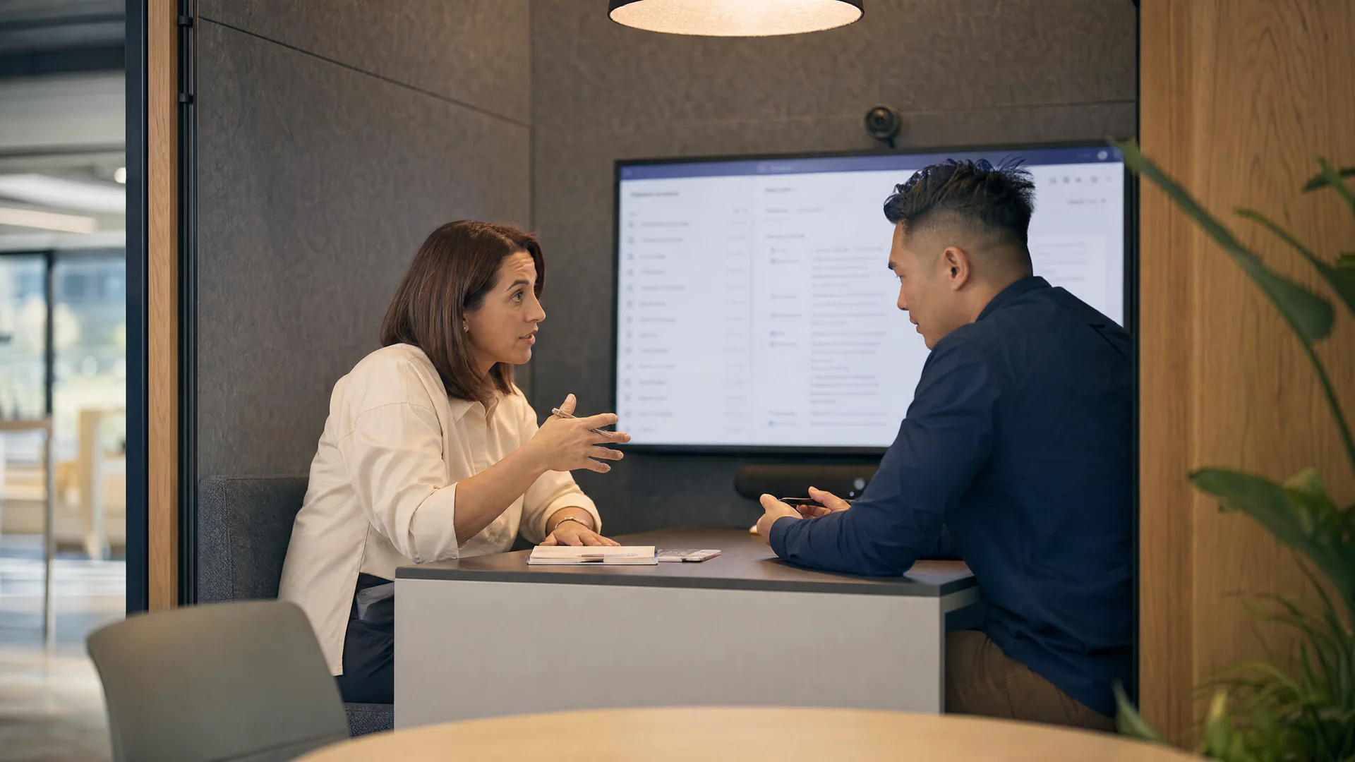 Two colleagues discuss a shared project in a quiet meeting booth.